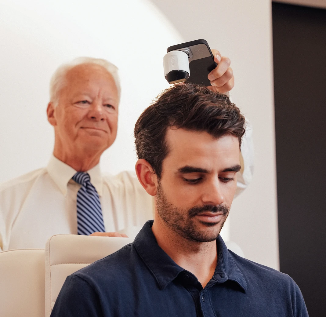 Dr. Keller uses a specialized handheld digital imaging device to perform a microscopic analysis of a male patient's hair and scalp.