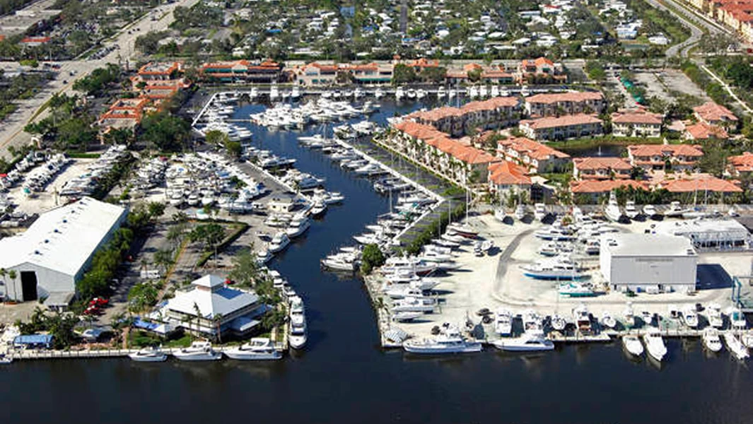 An aerial view of a Get Hair MD location situated within a waterfront complex featuring red-roofed buildings and a busy marina.