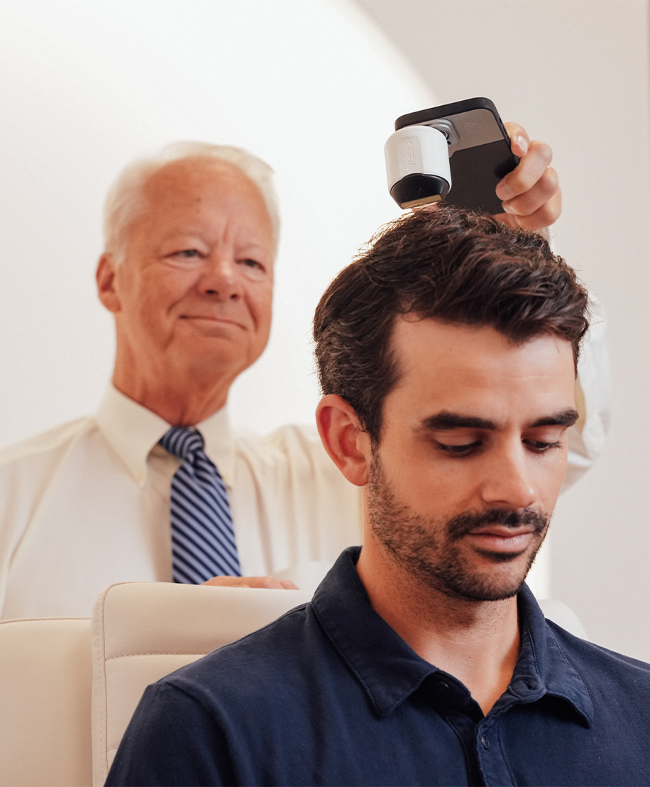 Dr. Keller uses a specialized handheld digital imaging device to perform a microscopic analysis of a male patient's hair and scalp.